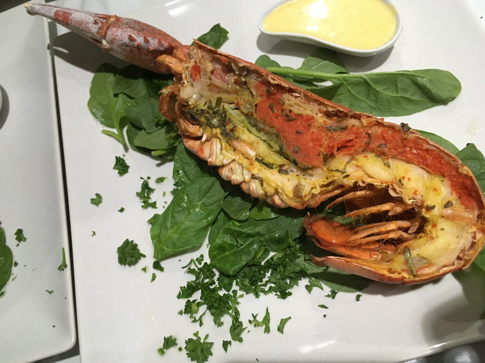 Grilled lobster tail with herbs and butter sauce on a bed of spinach